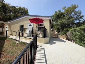 a house with a red umbrella on a balcony at Villadeco Escape, Gated Cottage with Generator in West End