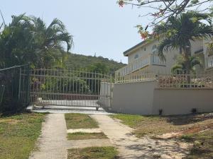 a gate in front of a house with palm trees at Villadeco Escape, Gated Cottage with Generator in West End +4 photos