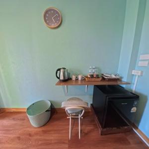 a clock on a wall above a table with a stool at Mocha Latte Homestay & Cafe in Chiang Rai