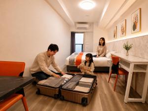 a man and a woman and a child in a room with luggage at Hotel Arashi Tengachaya No005 in Osaka