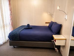 a bedroom with a large bed with a blue blanket at Shady Acres Caravan Park in Warrenheip
