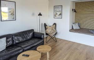 a living room with a black leather couch and a chair at 4 Bedroom Cozy Home In Haderslev in Haderslev