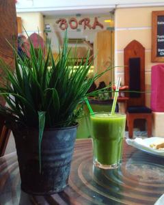 a green drink on a table with a potted plant at Bora Dormir in Lagos