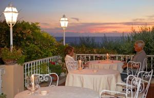 a man and a woman sitting at tables on a balcony at Romantic Hotel & Restaurant Villa Cheta Elite in Maratea