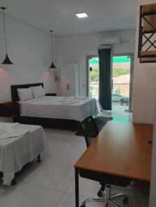 a room with two beds and a table and chairs at Suíte Lençóis - Quarto amplo com Cozinha Integrada in Lençóis