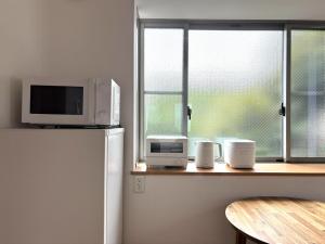 a kitchen with a microwave on top of a refrigerator at 湘南で暮らすように泊まる一棟貸し U-house Shonan in Fujisawa