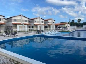 a swimming pool at a resort with white chairs at Reserva Aconchegante perto Praias, Aeroporto, UFDPar, UESPi in Parnaíba