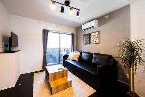 a living room with a black leather couch and a window at エルモス唐人 in Muromimachi