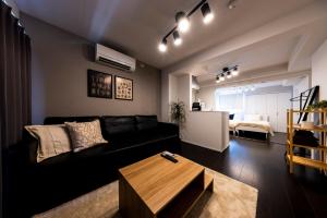 a living room with a black couch and a table at エルモス唐人 in Muromimachi