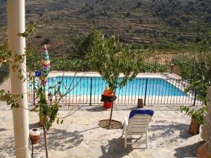 a swimming pool with a chair and a tree next to it at 4-Guest Laroya Cottage with Pool in Laroya