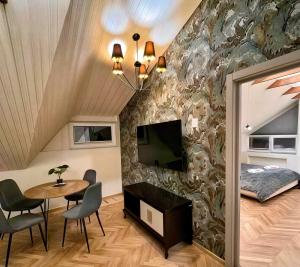 a living room with a table and a tv on a wall at Saules apartment Klaipeda in Klaipėda