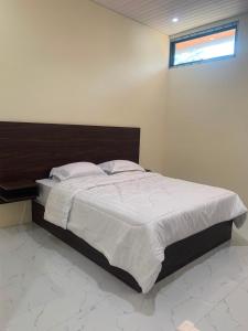 a bedroom with a large bed with a wooden headboard at Semar Hotel in Tjakranegara