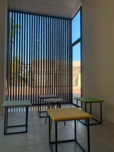 three tables and benches in a room with a large window at Semar Hotel in Tjakranegara