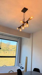 a dining room with a chandelier and a table and a window at Aconchego Serrano com banheira in Paty do Alferes