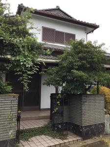 a house with a gate and two trees at いちご荘 in Ichihara
