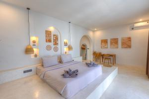 a bedroom with a white bed with purple flowers on it at Villa Afrodite in Gili Trawangan