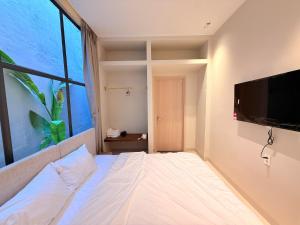 a bedroom with a bed with a flat screen tv at Villa Pii-House in Ấp Sung Xuân