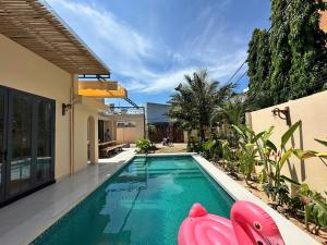 a swimming pool with pink inflatable chairs next to a house at Villa Pii-House in Ấp Sung Xuân