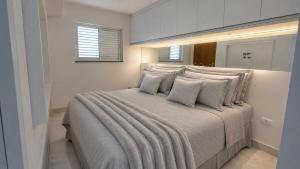 a white bedroom with a large bed with pillows at Recanto Veraneio in Londrina +12 photos