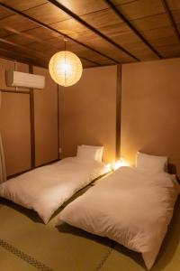two beds in a room with a chandelier at Yanagiya Iri in Nakatsugawa