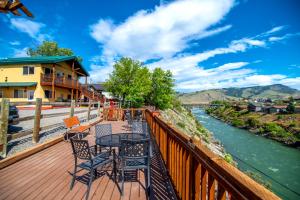 a deck with tables and chairs next to a river at Yellowstone Riverside Cottages in Gardiner