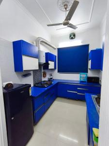 a blue kitchen with blue cabinets and a ceiling at Comfy Stay in Dehradun +33 photos