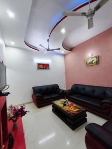 a living room with black couches and a ceiling at Comfy Stay in Dehradun