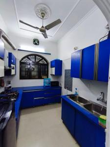 a kitchen with blue cabinets and a ceiling fan at Comfy Stay in Dehradun