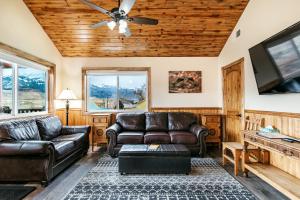 a living room with leather furniture and a flat screen tv at Yellowstone Riverside Cottages in Gardiner