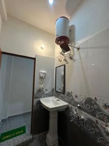 a bathroom with a sink and a light on the wall at The quiet corner homestay in Rudraprayāg