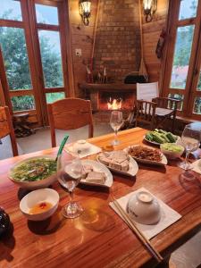 a wooden table with food and wine glasses and a fireplace at Coffee Myhome in Kon Rung (1)