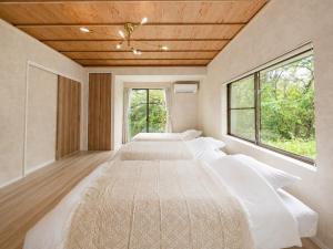 a row of beds in a room with windows at Knot in Shodoshima
