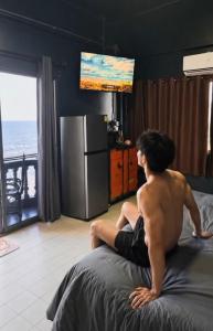 a shirtless man sitting on a bed in a bedroom at HiSSS Style ชะอำ in Cha Am
