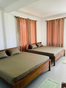 two beds sitting in a room with curtains at Relax Cottage in Mailagamuwa