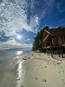 a beach with houses and footprints in the sand at KAINORA Guest Hause in Pulau Batanta