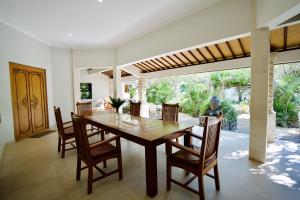 a dining room with a wooden table and chairs at Poinciana Resort in Tejakula