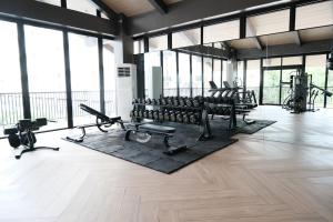 a gym with rows of exercise equipment and large windows at Airport Gem with Pool and Gym in Pusok