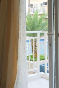 a room with a view of the ocean from a balcony at Airport Gem with Pool and Gym in Pusok
