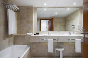 a bathroom with two sinks and a tub and a mirror at Meliá Benidorm in Benidorm