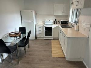 a kitchen with white appliances and a table and chairs at Comara Jindabyne Unit 2 in Jindabyne