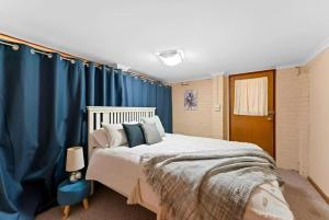 a bedroom with a large bed with blue curtains at Cheerful Beach house at Redhead - BBQ, Beach, Views in Redhead