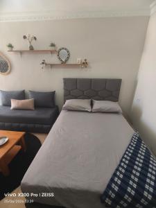 a bedroom with a large bed and a couch at Studio avec terrasse privée sans vis-à-vis in Essaouira
