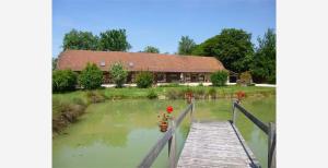 a house with a wooden bridge over a pond at La ferme d'aristide in Saillenard