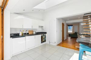 an open kitchen with white cabinets and a living room at Leafy Haven By My Getaways in Brighton & Hove