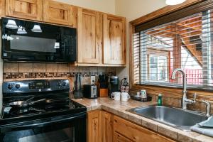 a kitchen with a stove and a sink and a microwave at Yellowstone Riverside Cottages in Gardiner +260 photos