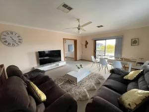 a living room with a couch and a clock on the wall at Cheerful Beach house at Redhead - BBQ, Beach, Views in Redhead