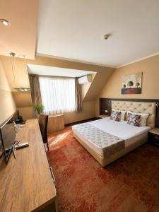 a hotel room with a bed and a desk and a desk at Business Hotel Plovdiv - Central Location in Plovdiv