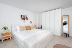 a white bedroom with a large bed and a mirror at Kata Station Boutique Hotel, Kata Beach in Kata Beach