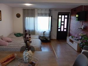 a living room with a table and a room with two beds at Studio apartman EMA in Brodski Varoš