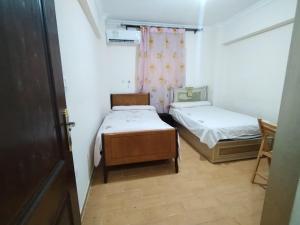 two beds in a small room with a window at Pink Horizon Homestay - for Men ONLY in Dumyāţ al Jadīdah